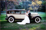 photo of a bride and groom in front of a vintage looking vehicle